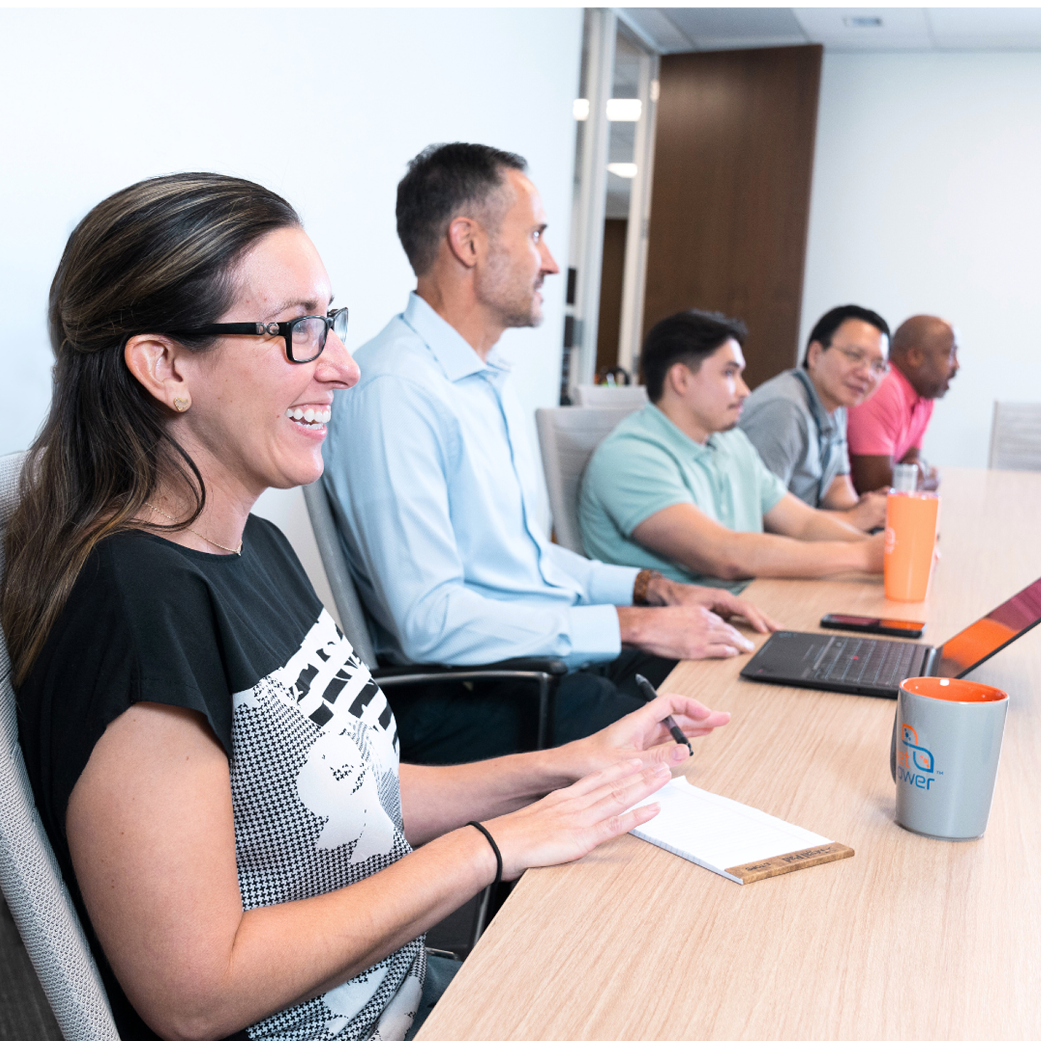 People seated at a conference table, engaged in a meeting.