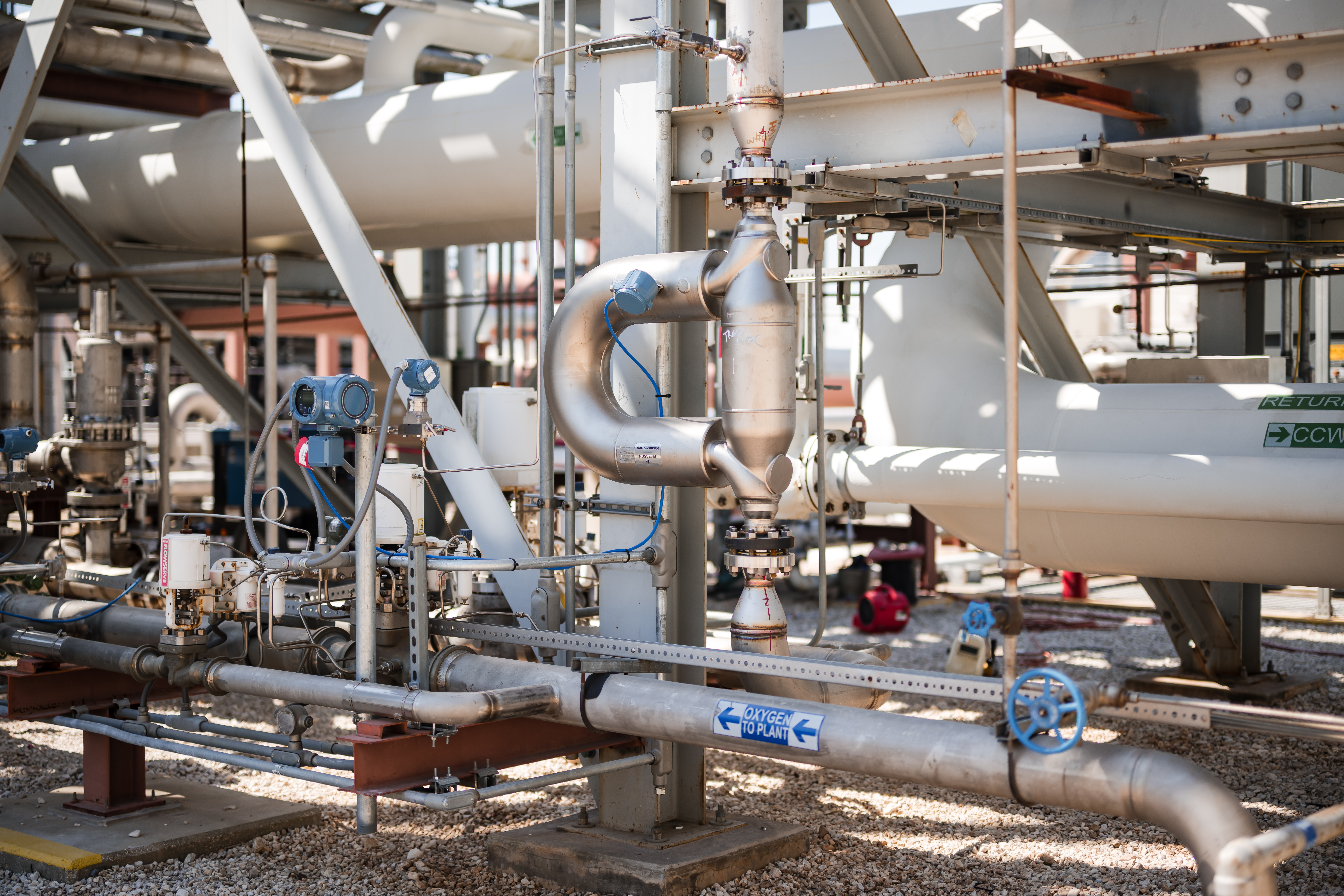 A complex industrial arrangement of pipes and machinery with labels indicating flow direction.